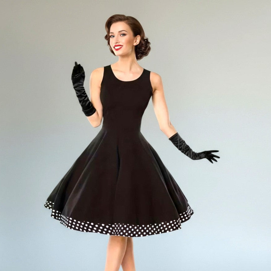 Woman wearing a black dress with a polka dot hem on a gray background