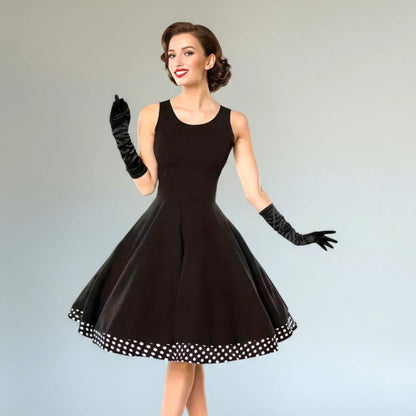 Woman wearing a black dress with a polka dot hem on a gray background